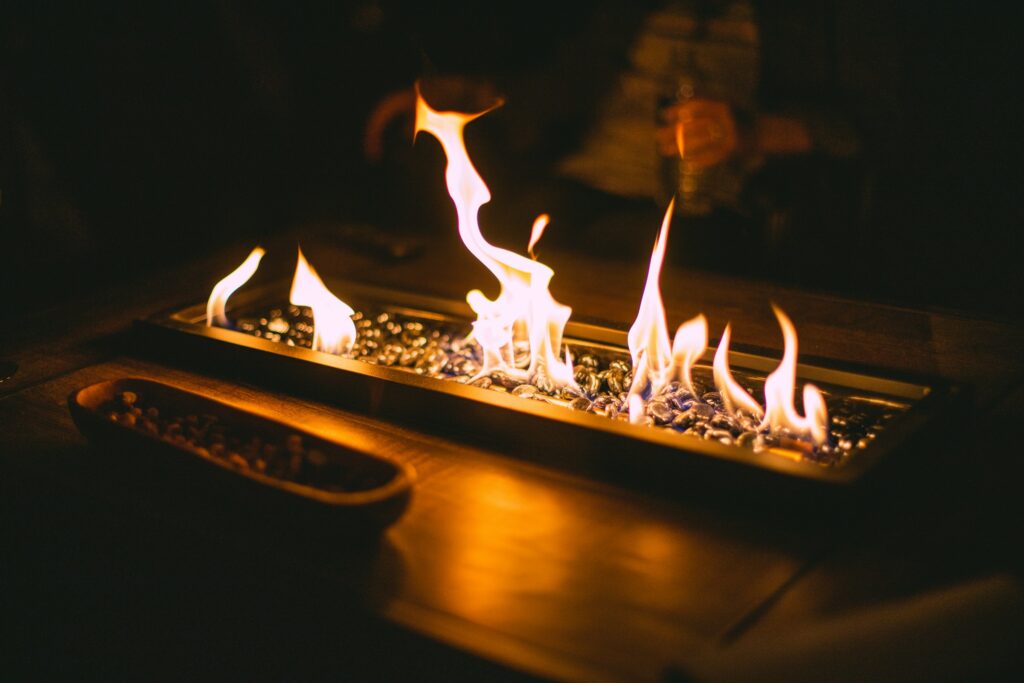 Länglicher Brenner mit offenen Flammen auf einem Holztisch, ohne Rauchrohr