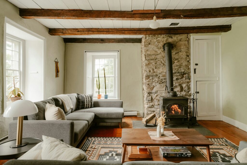 Brennender Kaminofen vor einer Wand aus Bruchstein, davor Sofa und Couchtisch